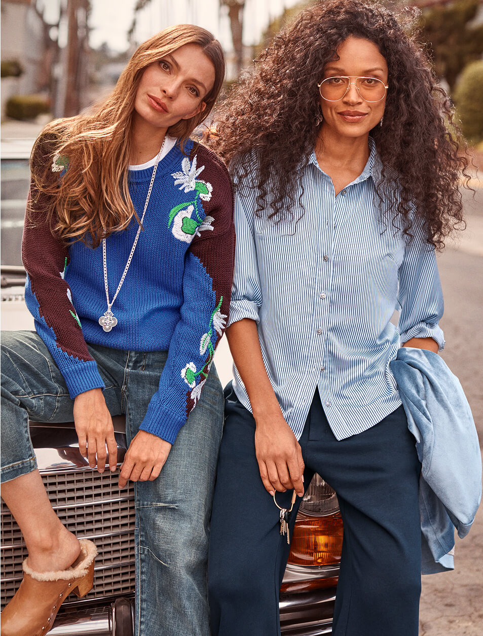 Two models sitting on the hood of a car, wearing items from cabi's Fall 2025 Collection.