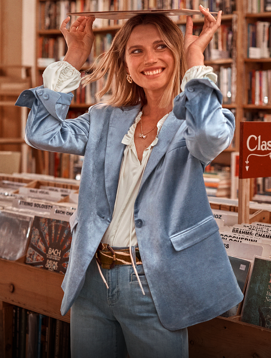 Model, standing in a record store, holding an album over head, dressed in the new cabi Fall 2025 Collection.
